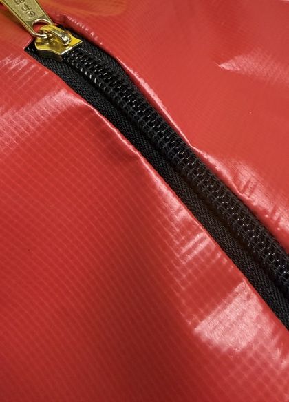 Close-up of the long zipper and its pull on the red vinyl bag.